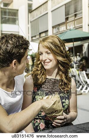 Stock Photograph - Young couple sharing bag of food. Fotosearch