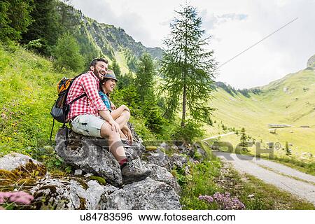 Stock Photograph - Young couple sitting on rocks, Tyrol, Austria. Fotosearch