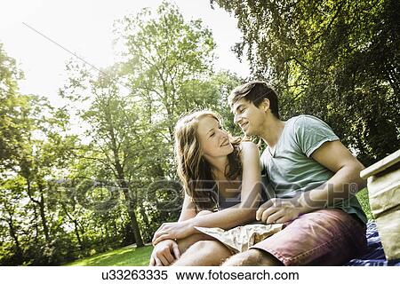Stock Photography - Young couple sitting together in park. Fotosearch