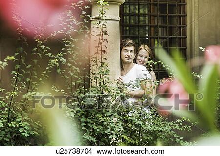 Young couple standing against pillar in garden View Large Photo Image Picture - Young couple standing against pillar in garden. Fotosearch