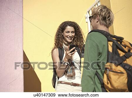 Young couple standing outside painted house chatting View Large Photo Image Stock Photo - Young couple standing outside painted house chatting. Fotosearch