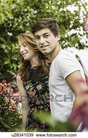 Young couple surrounded by foliage and flowers View Large Photo Image Stock Photo - Young couple surrounded by foliage and flowers. Fotosearch