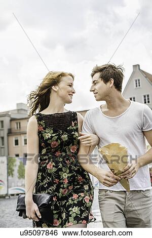 Stock Photograph - Young couple walking through town arm in arm. Fotosearch