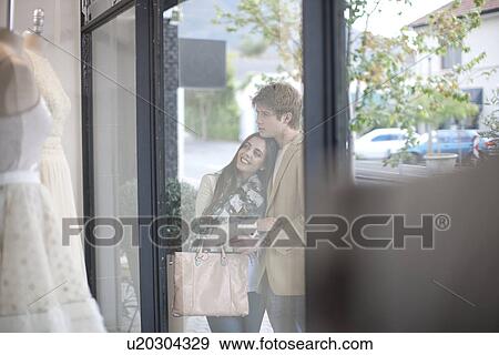 Young couple window shopping, looking through shop front View Large Photo Image Stock Photo - Young couple window shopping, looking through shop front. Fotosearch
