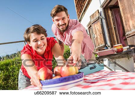 Young couple with apples outside chalet, Tyrol, Austria View Large Photo Image Stock Photo - Young couple with apples outside chalet, Tyrol, Austria. Fotosearch