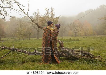Picture - Young couple wrapped in blanket in misty park. Fotosearch