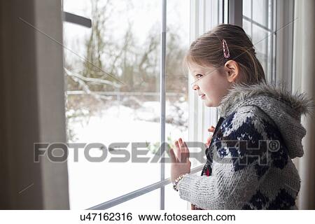 Young girl looking out of window at garden in snow View Large Photo Image Stock Photograph - Young girl looking out of window at garden in snow. Fotosearch