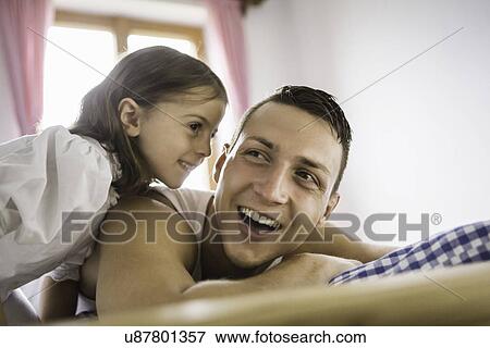 Young man and daughter on bed in holiday chalet, Tyrol, Austria View Large Photo Image Stock Photo - Young man and daughter on bed in holiday chalet, Tyrol, Austria. Fotosearch
