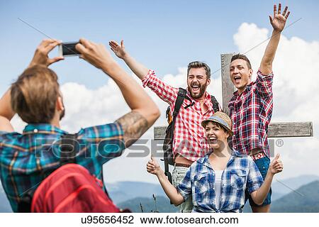Young man photographing friends by cross View Large Photo Image Stock Image - Young man photographing friends by cross. Fotosearch