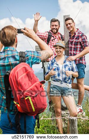 Young man photographing friends by cross View Large Photo Image Stock Photo - Young man photographing friends by cross. Fotosearch