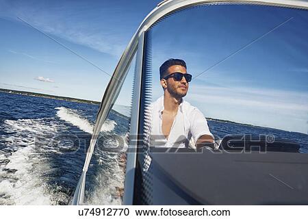Young man steering boat, Gavle, Sweden View Large Photo Image Stock Image - Young man steering boat, Gavle, Sweden. Fotosearch