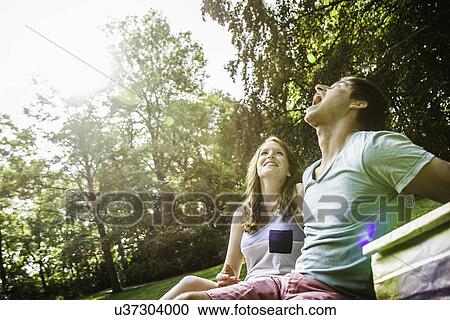 Young man trying to catch grape in his mouth, sitting with girlfriend in park View Large Photo Image Stock Image - Young man trying to catch grape in his mouth, sitting with girlfriend in park. Fotosearch