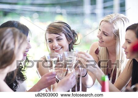 Young woman and friends toasting with glass of champagne View Large Photo Image Stock Image - Young woman and friends toasting with glass of champagne. Fotosearch