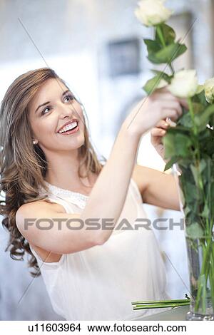 Young woman arranging bunch of roses in vase View Large Photo Image Picture - Young woman arranging bunch of roses in vase. Fotosearch