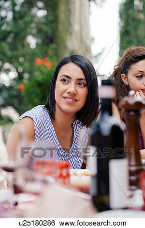 Stock Photograph - Young woman at family meal outdoors. Fotosearch