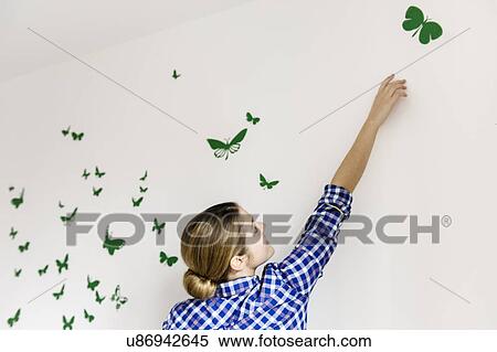 Young woman decorating wall with green butterflies View Large Photo Image Stock Photography - Young woman decorating wall with green butterflies. Fotosearch