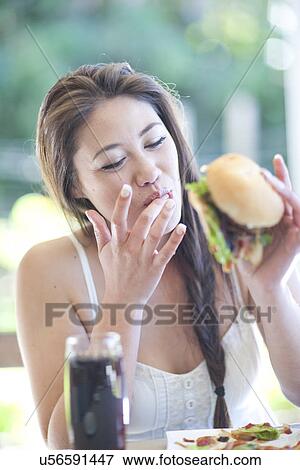 Young woman enjoying a burger View Large Photo Image Stock Photo - Young woman enjoying a burger. Fotosearch