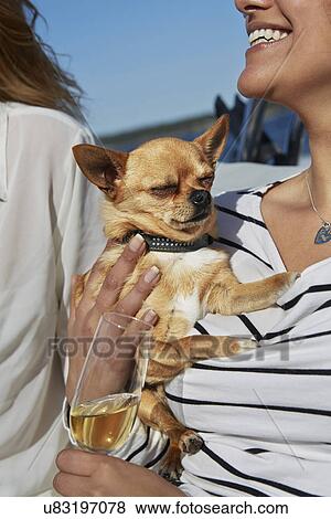 Stock Photo - Young woman holding dog and glass of wine. Fotosearch