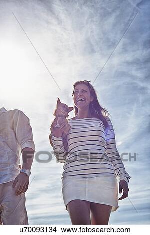 Young woman holding dog, low angle view View Large Photo Image Picture - Young woman holding dog, low angle view. Fotosearch
