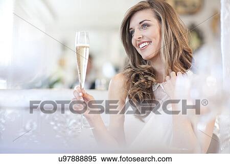 Stock Photography - Young woman holding glass of champagne. Fotosearch