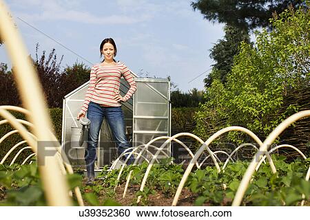 Stock Image - Young woman in vegetable garden. Fotosearch