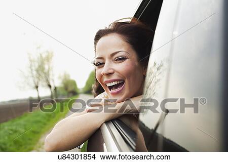 Young woman leaning out of car window, laughing View Large Photo Image Picture - Young woman leaning out of car window, laughing. Fotosearch