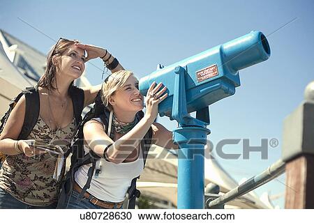 Stock Image - Young woman looking through telescope. Fotosearch