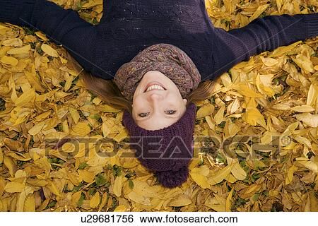 Young woman lying in autumn leaves View Large Photo Image Stock Photograph - Young woman lying in autumn leaves. Fotosearch