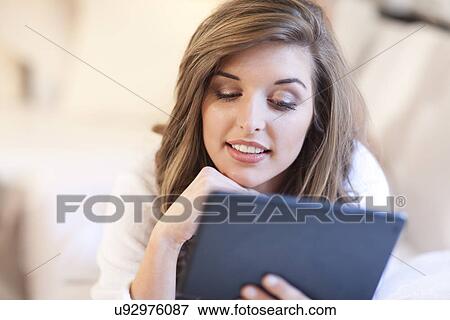 Young woman lying in bed with digital tablet View Large Photo Image Stock Photo - Young woman lying in bed with digital tablet. Fotosearch