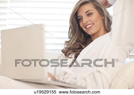 Stock Photography - Young woman lying in bed with laptop. Fotosearch