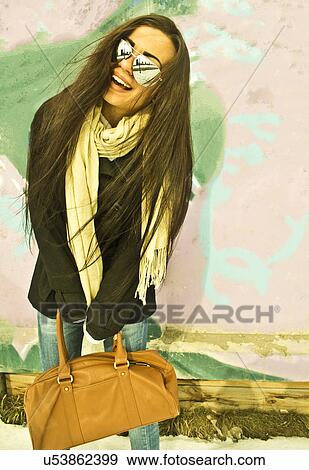 Young woman posing in front of painted wall View Large Photo Image Stock Photo - Young woman posing in front of painted wall. Fotosearch