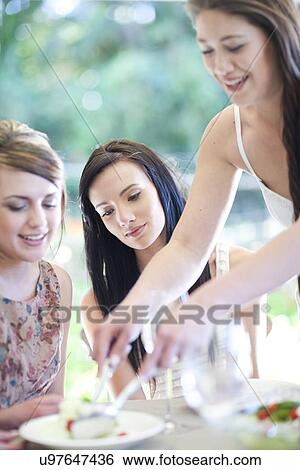 Young woman serving meal to friends View Large Photo Image Stock Photograph - Young woman serving meal to friends. Fotosearch