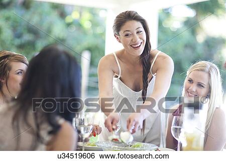 Young woman sharing meal with friends View Large Photo Image Stock Photograph - Young woman sharing meal with friends. Fotosearch