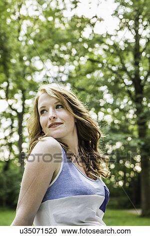 Young woman sitting in park View Large Photo Image Stock Image - Young woman sitting in park. Fotosearch