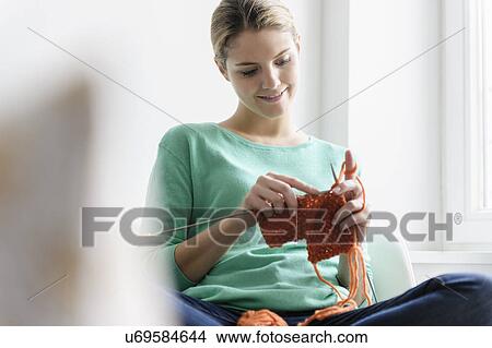 Young woman sitting in window seat knitting View Large Photo Image Picture - Young woman sitting in window seat knitting. Fotosearch