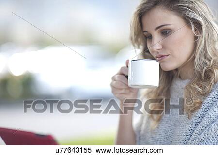 Young woman sitting outside cafe with cup of coffee and digital tablet View Large Photo Image Stock Photography - Young woman sitting outside cafe with cup of coffee and digital tablet. Fotosearch