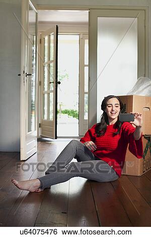 Young woman taking self portrait in new house View Large Photo Image Stock Photograph - Young woman taking self portrait in new house. Fotosearch
