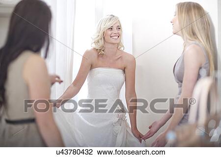 Young woman trying on wedding dress, with friends View Large Photo Image Stock Image - Young woman trying on wedding dress, with friends. Fotosearch
