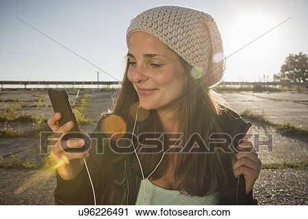 Stock Image - Young woman wearing earphones listening to music. Fotosearch