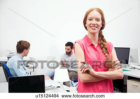 Picture - Young woman wearing pink blouse in office. Fotosearch