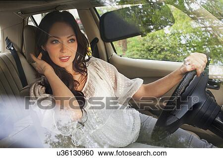 Young woman with hand in hair in car View Large Photo Image Stock Image - Young woman with hand in hair in car. Fotosearch