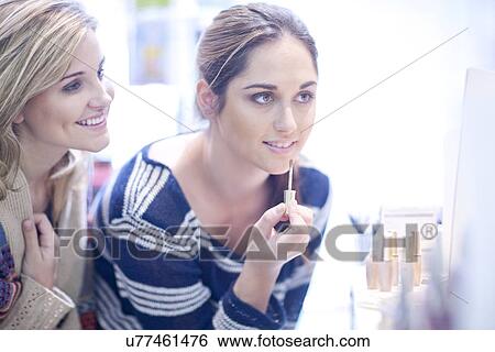 Stock Photograph - Young women applying make up. Fotosearch