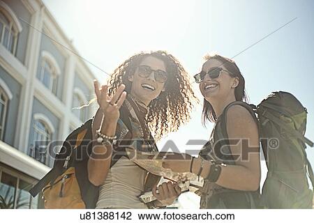 Young women standing in street holding map View Large Photo Image Stock Image - Young women standing in street holding map. Fotosearch