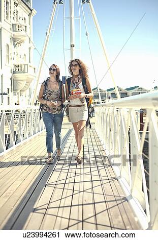 Stock Image - Young women walking along pier, Cape Town, South Africa. Fotosearch