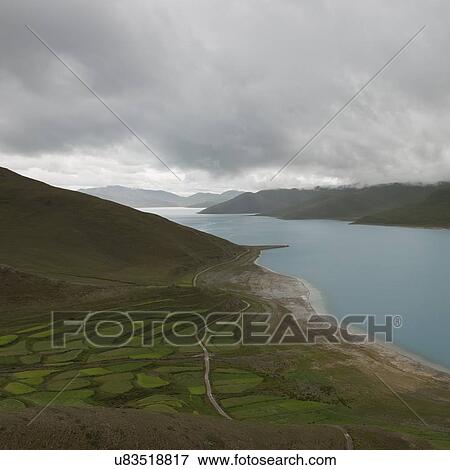 Stock Photo - Aerial view of road passing through agricultural fields along Yamdrok Lake, Nagarze, Shannan, Tibet, China. Fotosearch