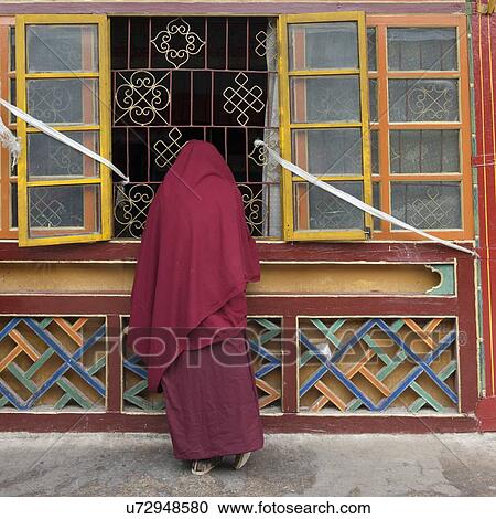 Stock Image - Buddhist monk standing at a window in Drepung Monastery, Lhasa, Tibet, China. Fotosearch