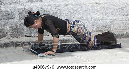 Stock Photograph - Buddhist woman prostrating on a street, Barkhor, Lhasa, Tibet, China. Fotosearch