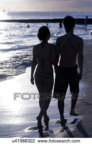Stock Image - Couple walking with holding hands on the beach, Waikiki, Honolulu, Oahu, Hawaii, USA. Fotosearch