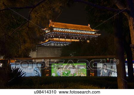 Stock Image - Digital screens in front of an illuminated building at Xi'an, China. Fotosearch
