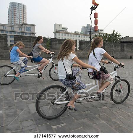 Happy mother with girls riding tandem bicycle at Xian City Wall, Xi'an, Shaanxi, China. View Large Photo Image Stock Photo - Happy mother with girls riding tandem bicycle at Xian City Wall, Xi'an, Shaanxi, China.. Fotosearch